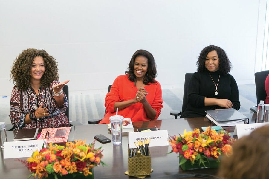 Michele Norris sits next to Michelle Obama during an event