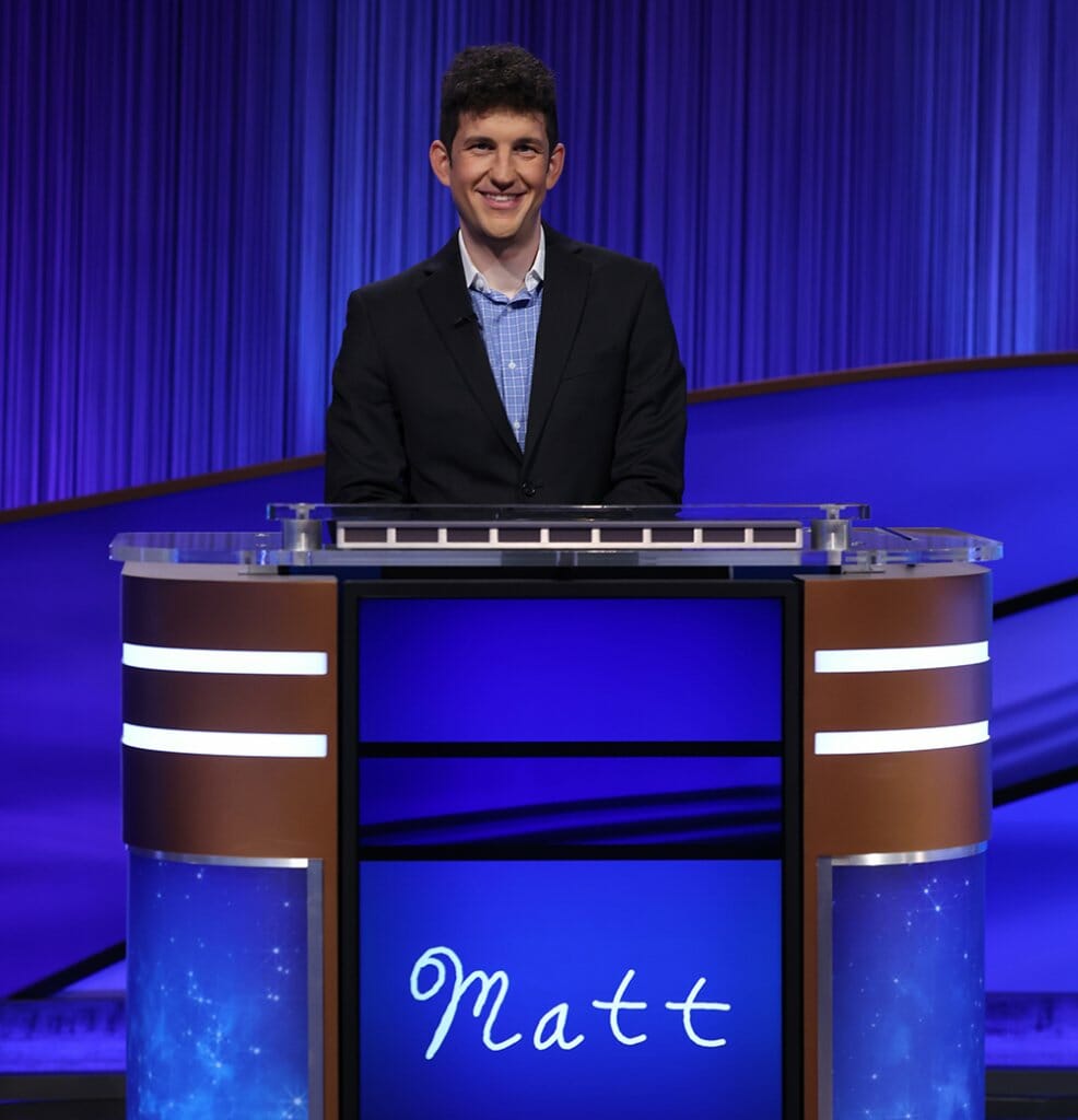Matt Amodio behind Jeopardy contestant podium with a screen displaying his handwritten name