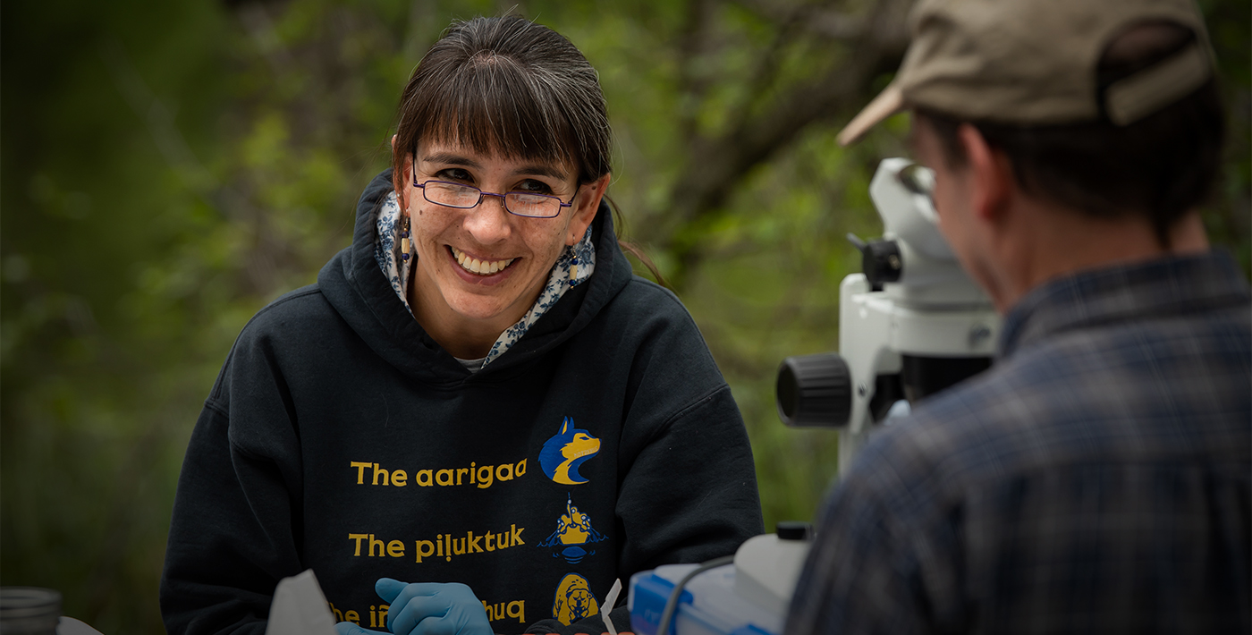 Kat Milligan-McClellan smiles at colleague over microscope