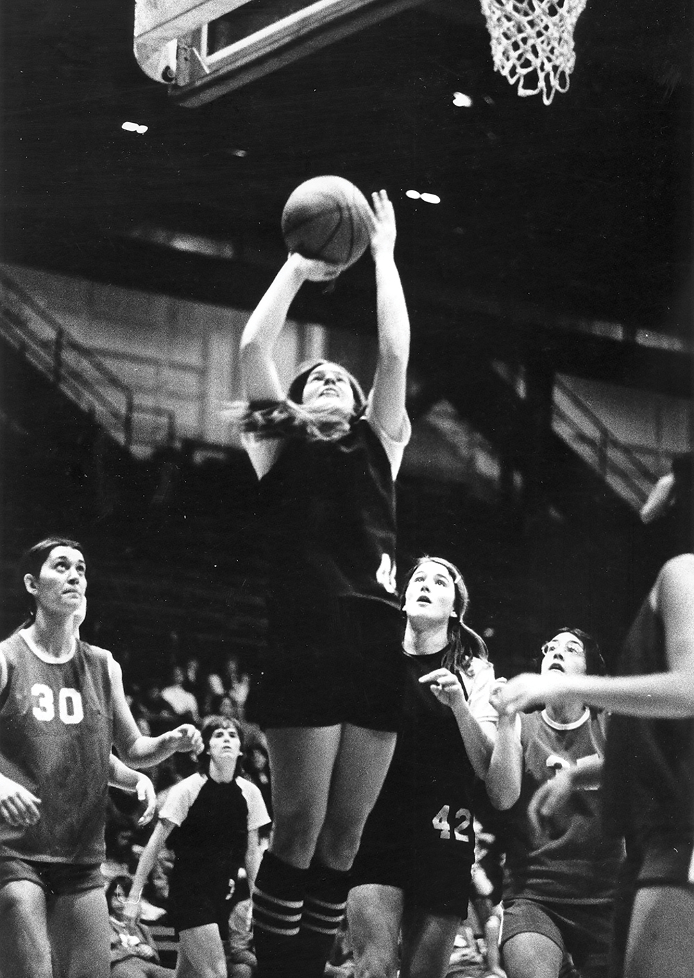 A 1974 black and white photo of a UW women's basketball player about to make a basket