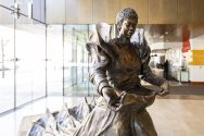 Photo of the front of The Sower bronze sculpture depicting a Black woman wearing a long flowing dress with an apron full of seeds.