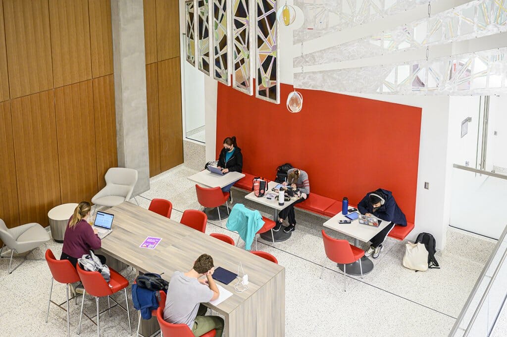 Students study, nap, and pass time in a brightly-decorated lobby area in the new UW–Madison Chemistry building.