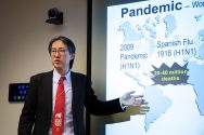 Prof. Yoshihiro Kawaoka gives a talk in front of a projector screen