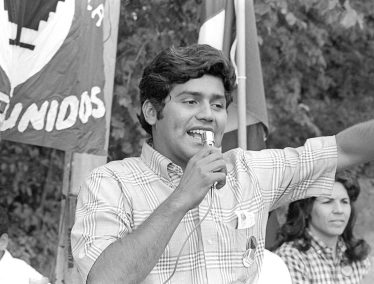 Black and white photo of Jesus Salas speaking into a microphone during a rally