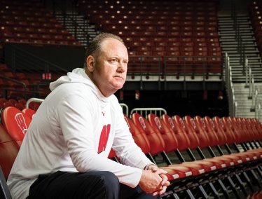 Greg Gard sits in the empty stands of the Kohl center