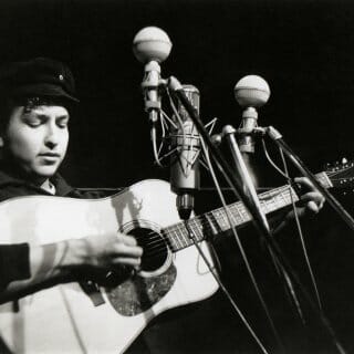 Black and white photo of young Bob Dylan performing onstage