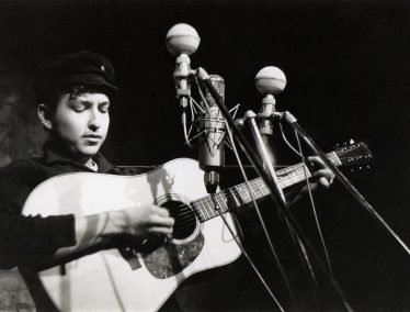 Black and white photo of young Bob Dylan performing onstage