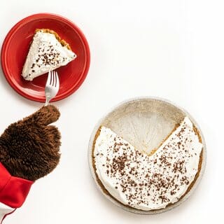 Bucky Badger's paws are shown digging into a piece of fudge bottom pie on a red plate with a fork