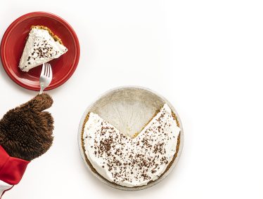 Bucky Badger's paws are shown digging into a piece of fudge bottom pie on a red plate with a fork
