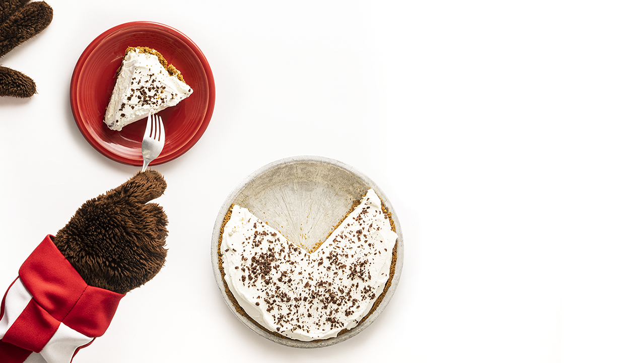 Bucky Badger's paws are shown digging into a piece of fudge bottom pie on a red plate with a fork