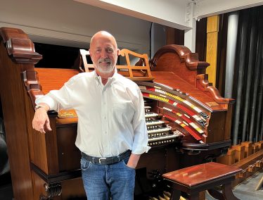 Paul Woelbing poses in front of a large organ
