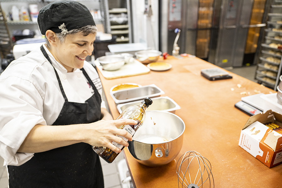 Smiling pastry chef pours vanilla extract into large bowl