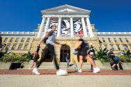 Students and pedestrians walk in front of Bascom Hall on a sunny warm day