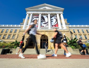 Students and pedestrians walk in front of Bascom Hall on a sunny warm day