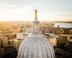 Wisconsin State capitol building dome and gold statue against backdrop of Madison downtown and Lake Mendota