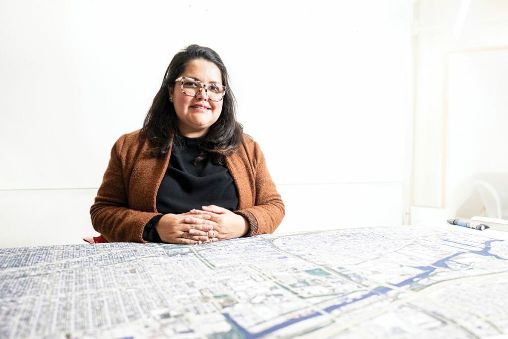 Edna Ledesma sits at a table on which a large map is spread out