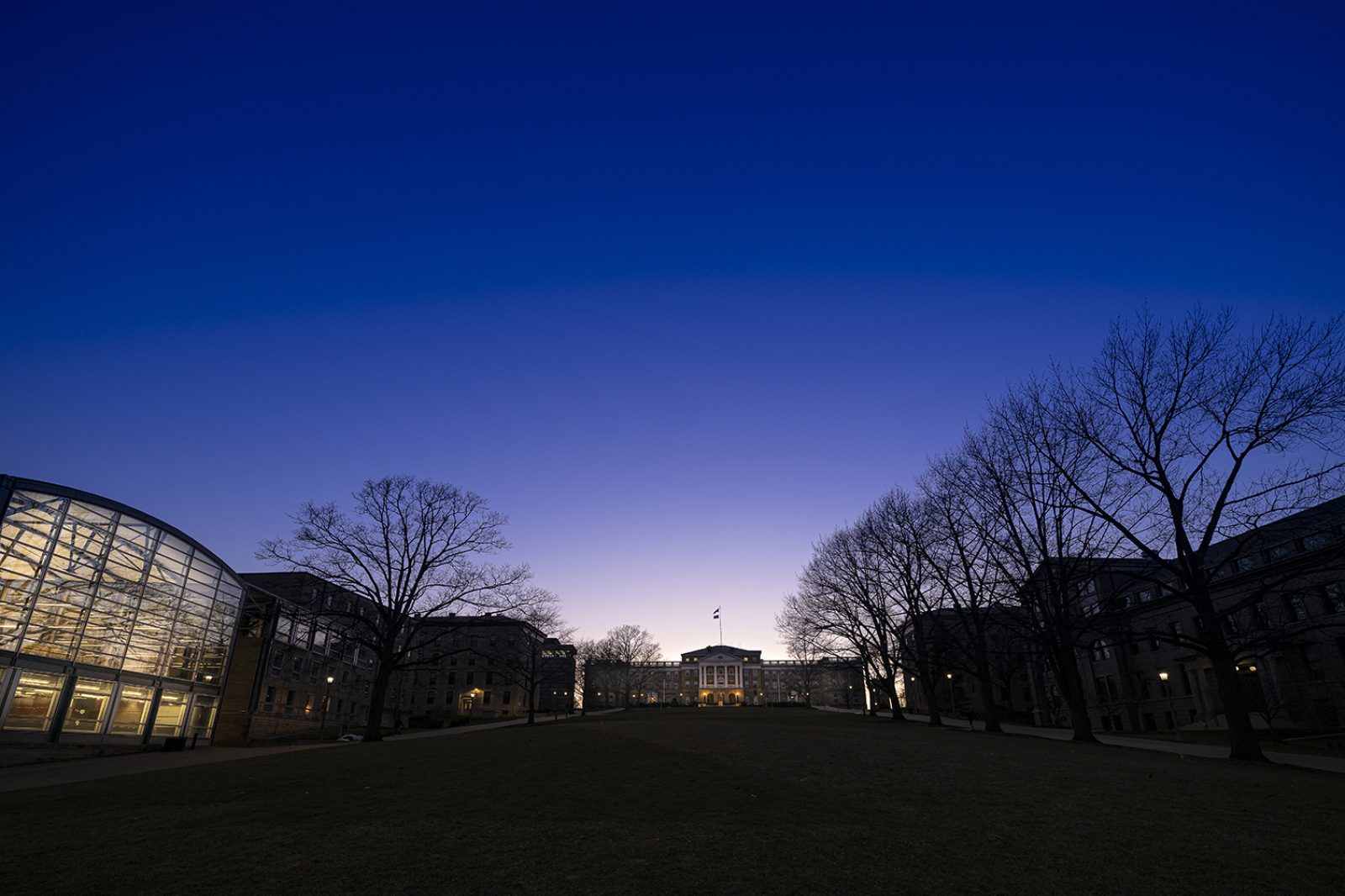 Last light of dusk is visible behind Bascom Hall with other Bascom Hill buildings and trees are silhouetted agains the dark blue sky