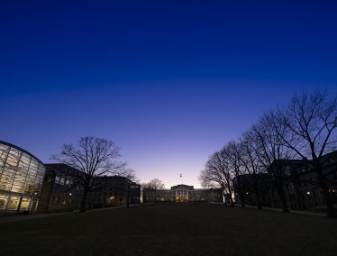 Last light of dusk is visible behind Bascom Hall with other Bascom Hill buildings and trees are silhouetted agains the dark blue sky