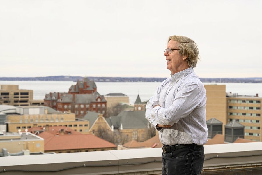 Robert Enright poses on rooftop overlooking the UW–Madison campus and Lake Mendota