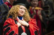 Jennifer Mnookin clasps hands in gesture of gratitude while wearing academic regalia
