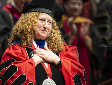Jennifer Mnookin clasps hands in gesture of gratitude while wearing academic regalia