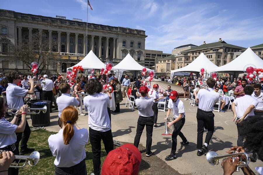 The UW Marching Band plays and red and white balloons decorate tables during a post-Investiture ceremony picnic on Library Mall at the University of Wisconsin–Madison on April 14, 2023. The picnic included live music, entertainment, free food, and the inaugural serving of Chancellor Mnookin’s ice cream flavor (Mnookie Dough). The event is part of Investiture Week, a series of special campus events planned for April 10-15 to celebrate the university and formally welcome Mnookin as chancellor. (Photo by Althea Dotzour / UW–Madison)