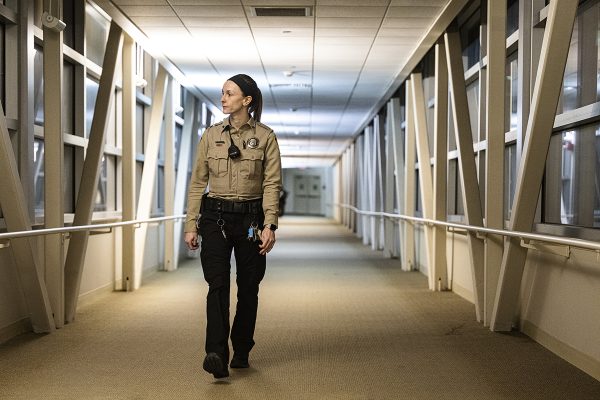 Megan Owen wearing a security guard uniform walks across an overpass
