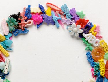 A portion of a colorful wreath made with children's discarded plastic hair clips.