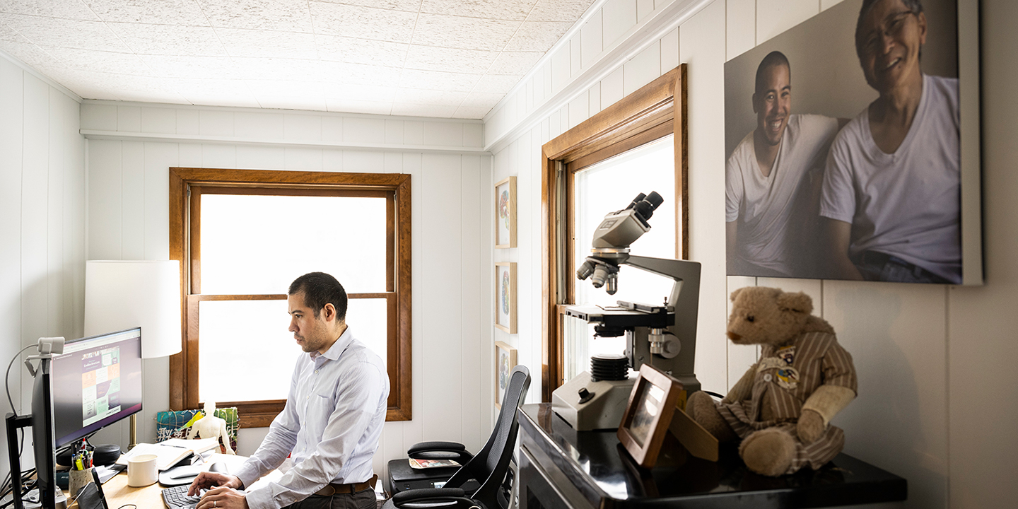 Nate Chin works at a computer in his home office, with keepsakes from his father nearby.