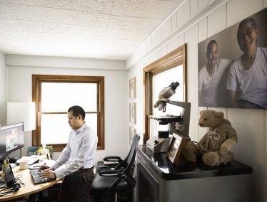 Nate Chin works at a computer in his home office, with keepsakes from his father nearby.
