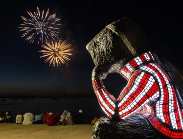 Statue of Bucky Badger against dark sky filled with fireworks