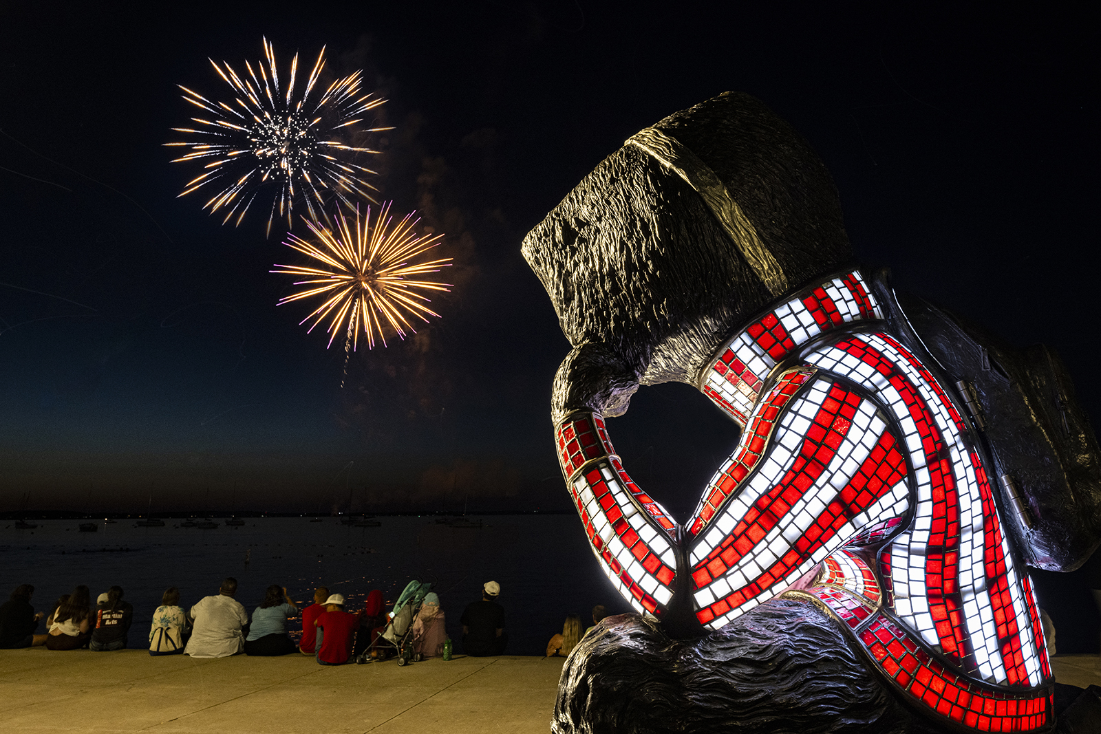 Statue of Bucky Badger against dark sky filled with fireworks
