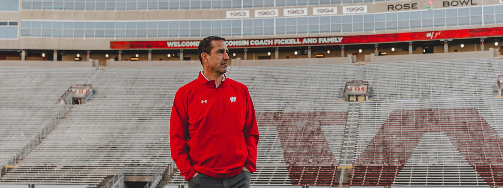 Luke Fickell wearing red Wisconsin polo on Camp Randall field