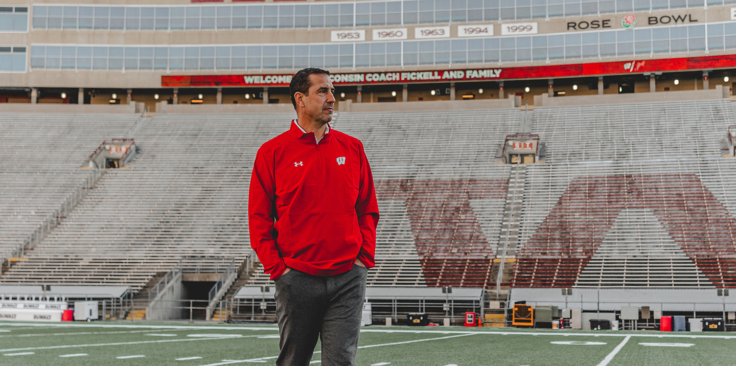 Luke Fickell wearing red Wisconsin polo on Camp Randall field