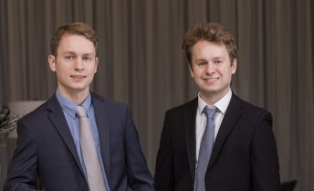 James and Chris Kardatzke smile wearing suits