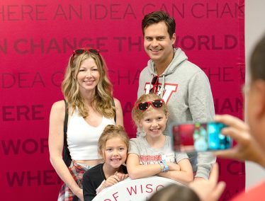 A family poses for a portrait in front of a red backdrop