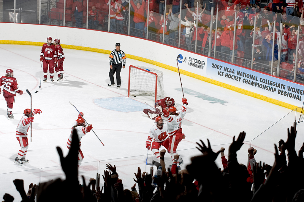 Badger hockey players rejoice on the ice after scoring.