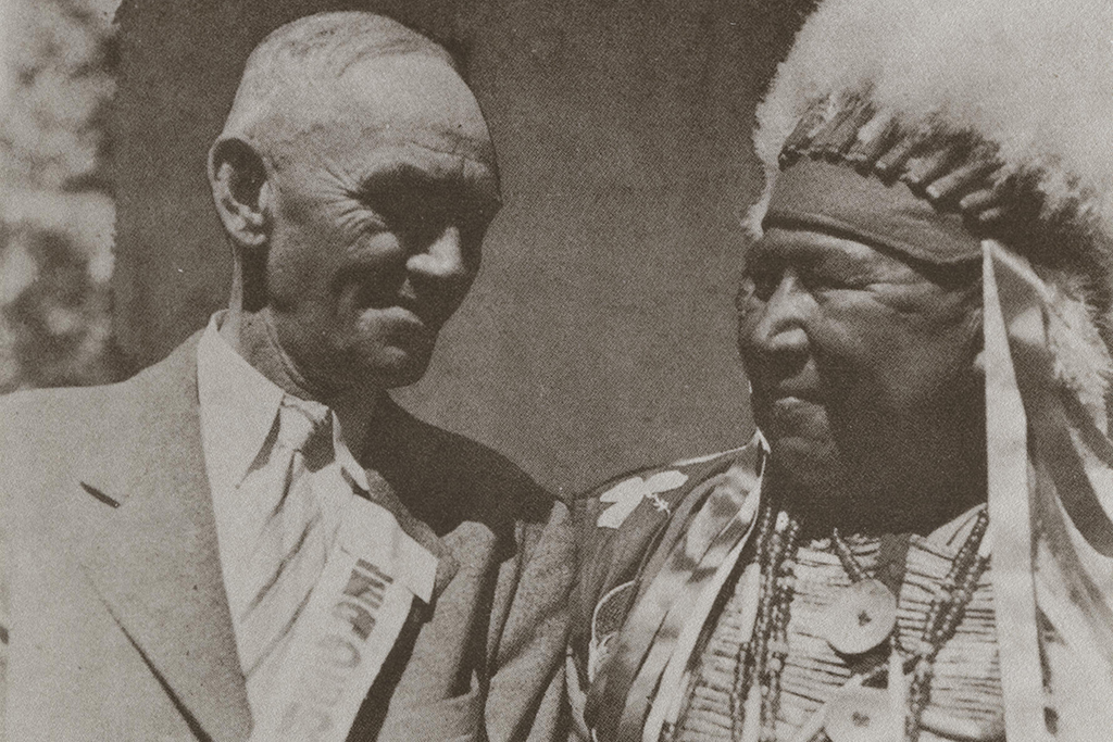 Charles E. Brown, in a suit, smiles at Chief Yellow Thunder, who is smiling back at him.