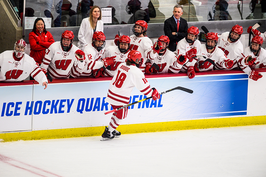 Abby Roque skates by her UW hockey team members as they cheer.