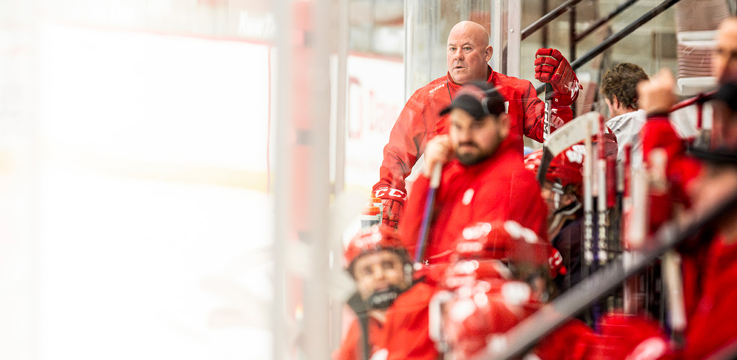 Coach Mike Hastings looks upon the ice at the end of the bench