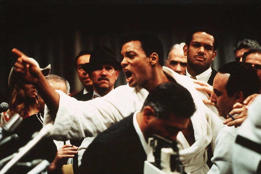 Still frame from the movie Ali, showing actor Will Smith as Muhammad Ali in a boxing robe, pointing and yelling.