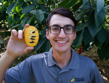 Adam D’Angelo holds up half a pawpaw fruit.