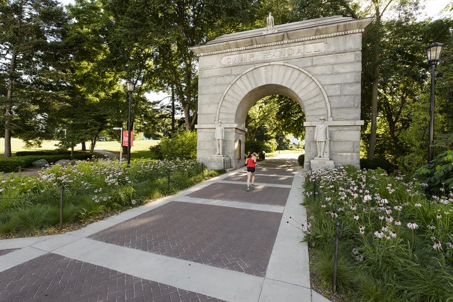 A jogger approaches Camp Randall Memorial arch during summertime