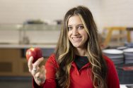 Jensen Skinner smiles and holds out an apple