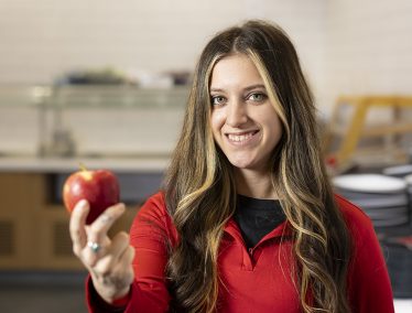 Jensen Skinner smiles and holds out an apple