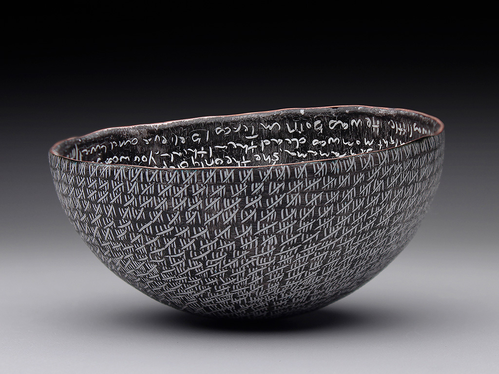 A bowl with white tally marks on black enamel on the outside, as seen from the side.