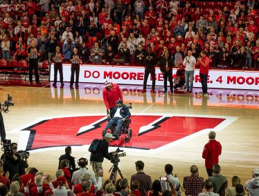 Howard Moore, in a wheelchair, in the center of the basketball court at the Kohl Center.