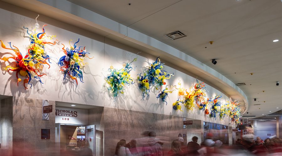 colorful Chihuly glass sculptures line a wall in the Kohl Center as patrons flow by