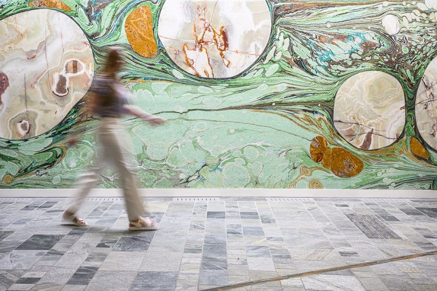 A person traverses the space in front of the Threshold mosaic