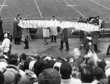 Black and white photo of people holding a large banner in front of a crowd that reads "Kennedy for Senator"